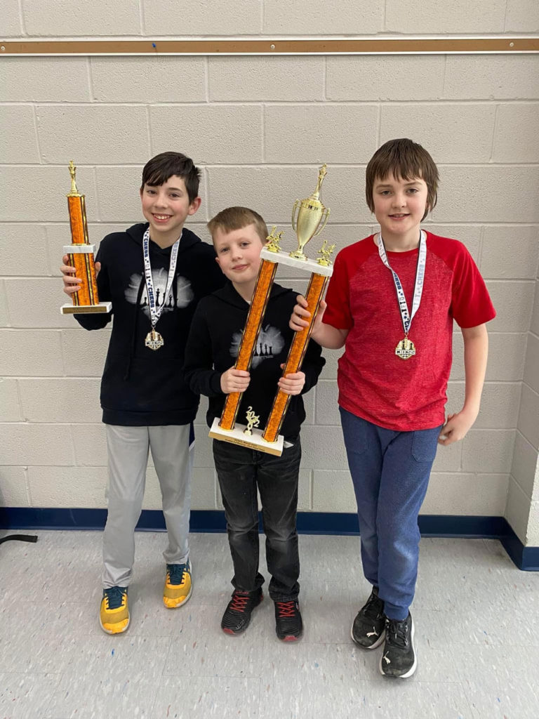 three chess team students with their trophies